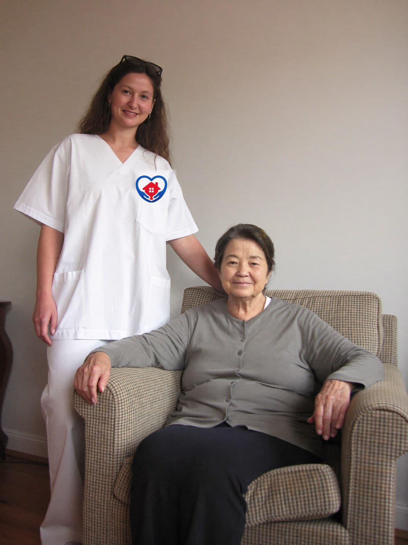 A MIRAY HOME HEALTH CARE caregiver wearing a white scrub top with the MIRAY HOME HEALTH CARE logo, standing with a client.